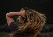 Woman tosses hair in meadow.