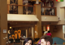 Spend a Saturday Exploring Aurora, One Stop at a Time A woman and man smile and share a meal together at a table inside a colorful, casual dining hall.