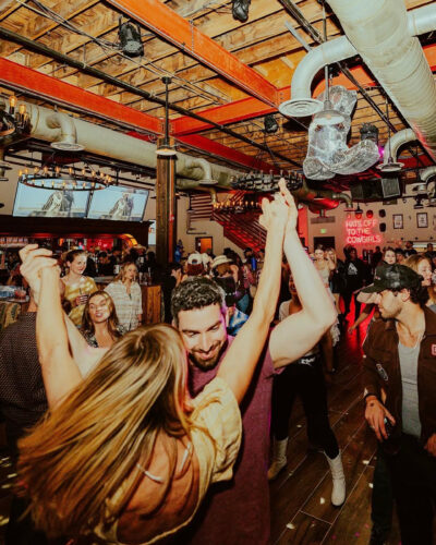 People dance under Abstruse's disco cowboy boot at Belles and Boots.