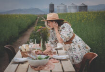 Woman looks over products from Wendi’s Good Things Market in a field.