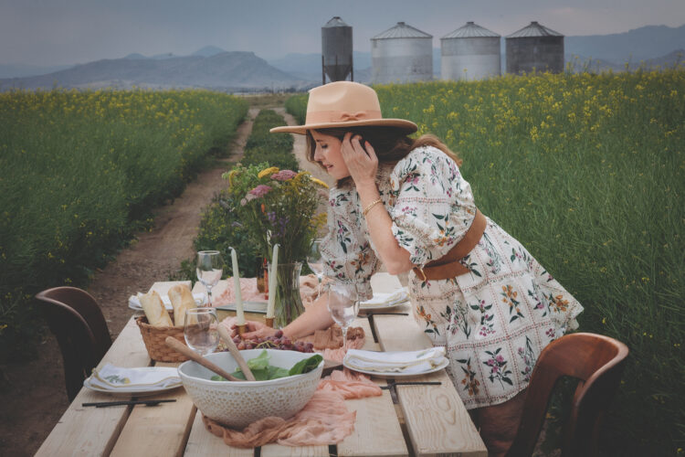 Woman looks over products from Wendi’s Good Things Market in a field.