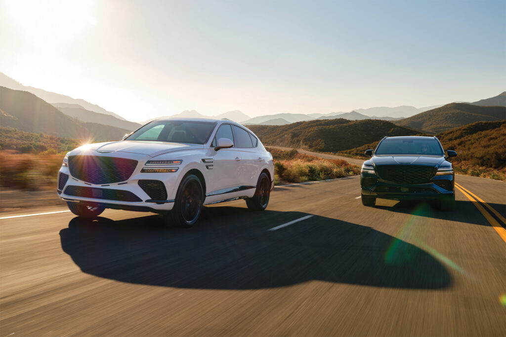 Two 2026 Genesis GV80 SUV's race alongside each other on an open road.