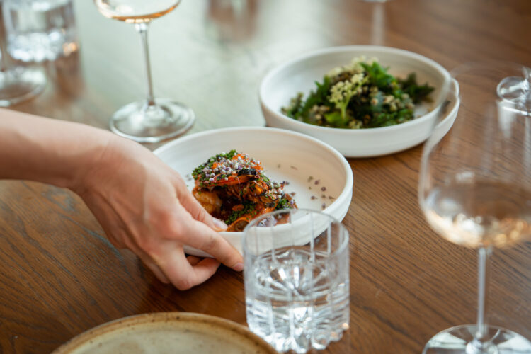Person places dishes on a table at chef Kelly Whitaker's SHEEP.