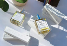 Wit & West perfume bottles and packaging arranged on a white surface in sunlight, featuring the Streetcar Magnolia and Yuzu Pop fragrances.