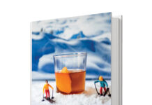 Cover of Alpine Cocktails, edited by Allyson Reedy, featuring a cocktail surrounded by miniature skiers in a snowy mountain scene.