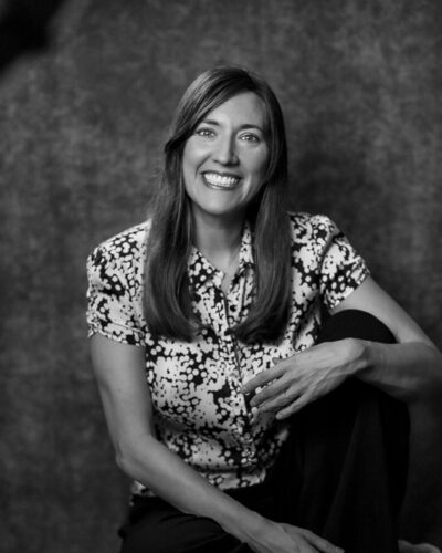 Black-and-white portrait of Alpine Cocktails editor Allyson Reedy smiling against a textured backdrop.