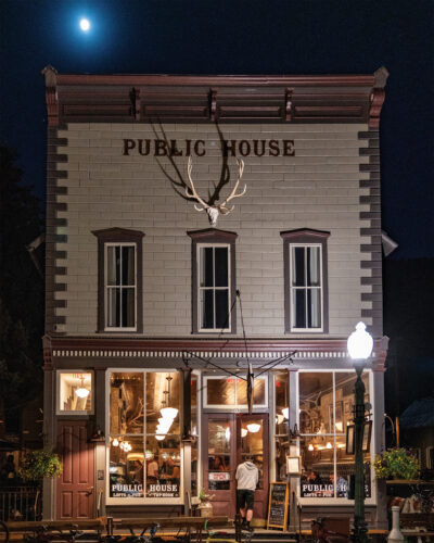 Public House building illuminated at night beneath the moon, with guests visible inside the pub.