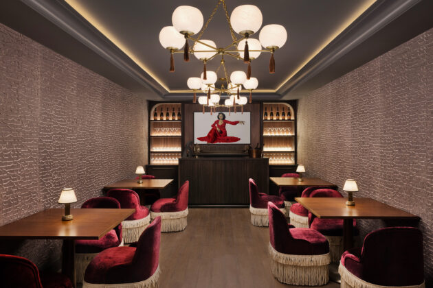 Intimate dining room with burgundy velvet chairs, globe chandeliers, textured walls, and a private bar.
