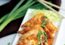 Crispy fried wontons topped with sesame seeds, green onions, and a savory orange sauce.