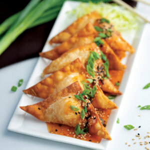 Crispy fried wontons topped with sesame seeds, green onions, and a savory orange sauce.