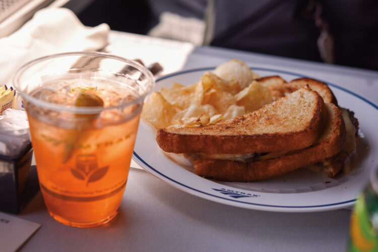 Grilled sandwich, potato chips and a drink served aboard an Amtrak train.