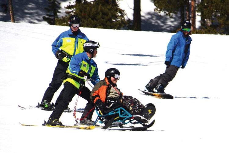 Man in seated adaptive ski chair skis down the mountain with Ignite Adaptive Sports.