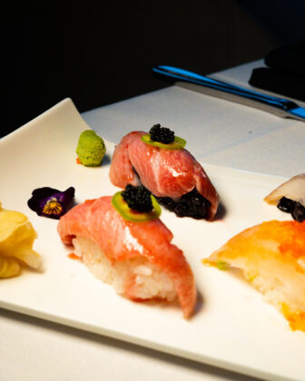 Assorted sushi and nigiri topped with caviar and garnishes on a white plate.