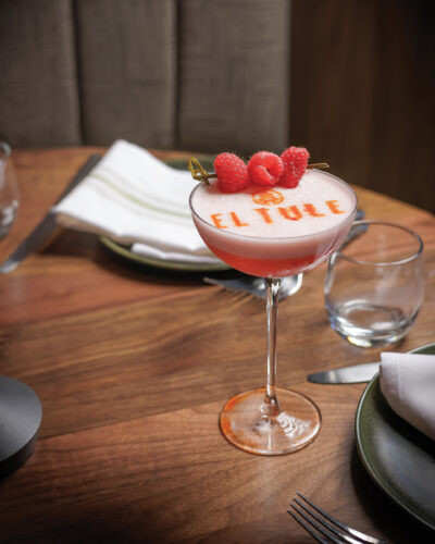 Raspberry cocktail with “El Tule” stenciled across the foam on a restaurant table.