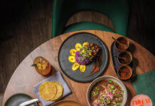 Overhead view of an El Tule dining spread with steak, braised meat, tortillas, churros, cocktails and other dishes.