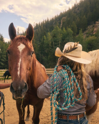 A female wrangler cares for a horse at Tumbling River Ranch.