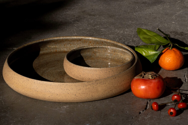 Speckled ceramic serving dish and matching bowl beside fruit from Twisted Pine Pottery.