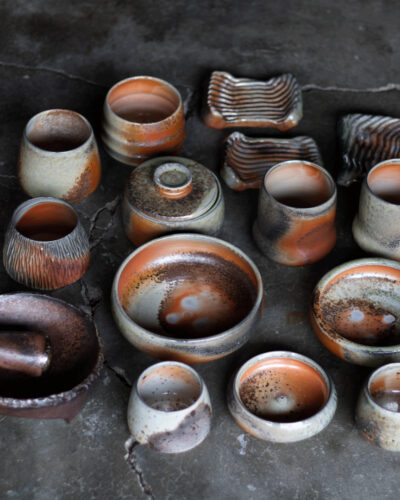 Twisted Pine Pottery cups, bowls, and dishes with mottled orange, gray, and cream surfaces.