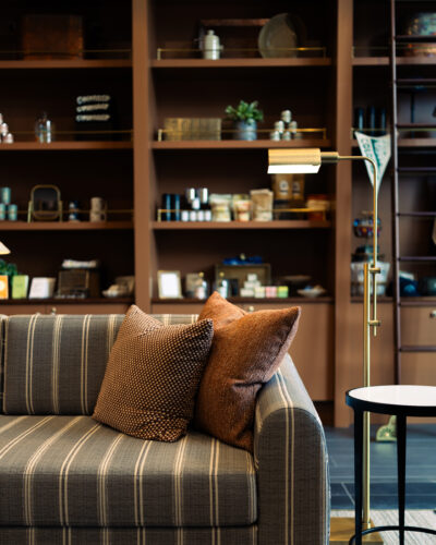 Striped sofa with textured pillows beside a brass reading lamp at Hotel Longmont.