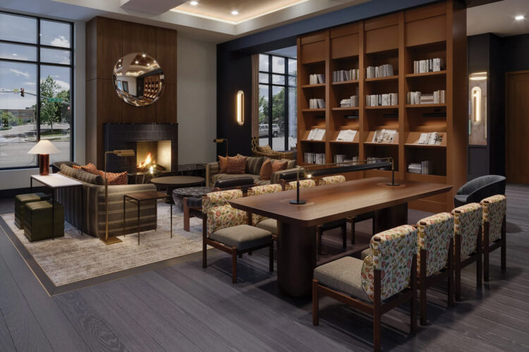 Hotel Longmont lobby with a fireplace, bookshelves, and a communal reading table.