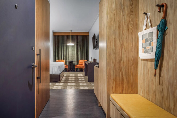 Hotel Longmont guest room entrance with a tote bag, umbrella, and orange seating.