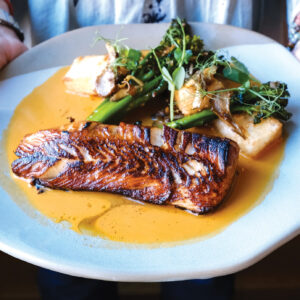 Person presents the Urban Farmer Seared Black Cod.