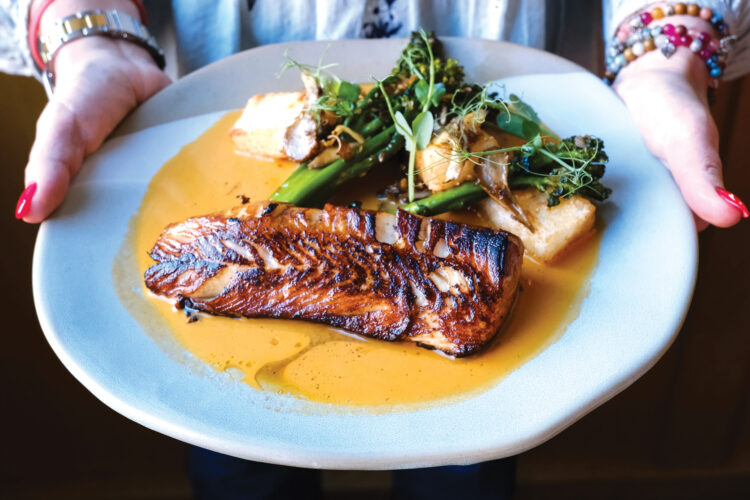 Person presents the Urban Farmer Seared Black Cod.
