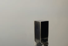 Ian Houghton Forges a Softer Side of Steel Tall rectangular metal sculpture with a folded, pinched center on a white pedestal.