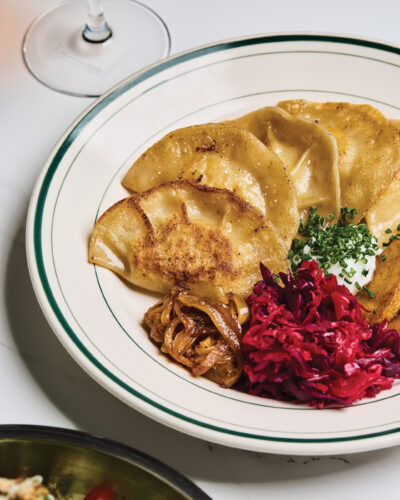 Golden pan-fried dumplings served with caramelized onions, shredded red cabbage, and chive-topped sauce.