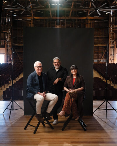 Artists and makers pose on a stage together.
