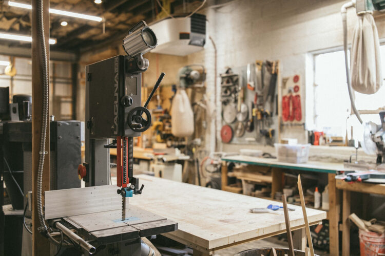 A band saw, worktables, and wall-mounted tools in ReCreative Denver’s woodshop.